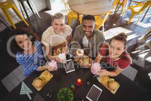 High angle portrait of smiling young friends sitting with lunch at coffee shop