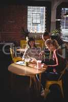 Young friends talking while man pointing at digital tablet