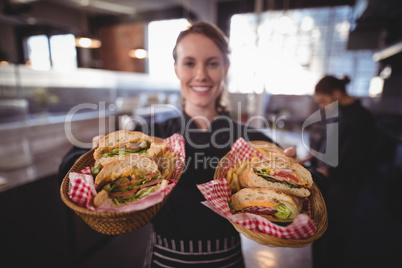Portrait of smiling young waitress serving fresh burgers at coffee shop