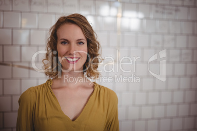 Portrait of smiling young female customer standing against white wall