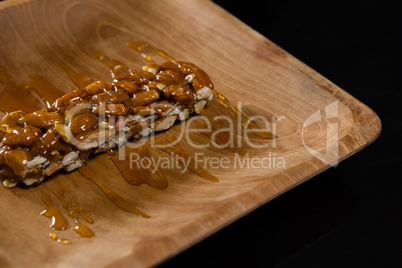 Honey on granola bar in wooden plate