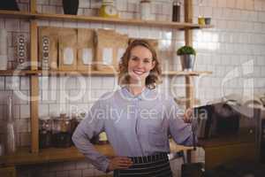 Portrait of confident young waitress standing with hand on hip