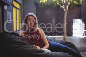 Portrait of beautiful young female customer sitting on bean bag