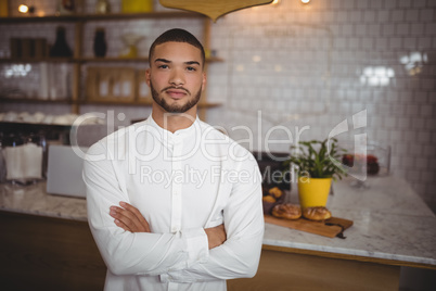 Portrait of confident young man standing with arms crossed