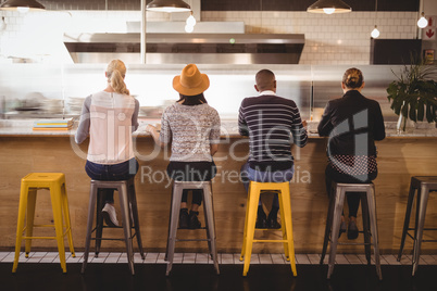 Rear view of customers sitting on stools at counter