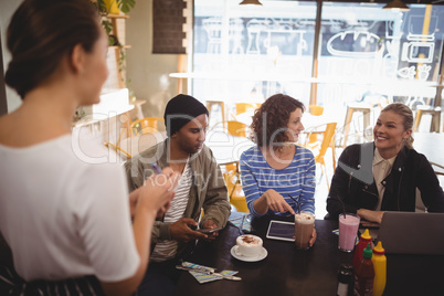 Smiling woman siting with friends ordering food to waitress