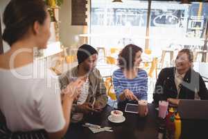 Smiling woman siting with friends ordering food to waitress