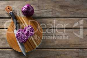 Red cabbage with knife on chopping board