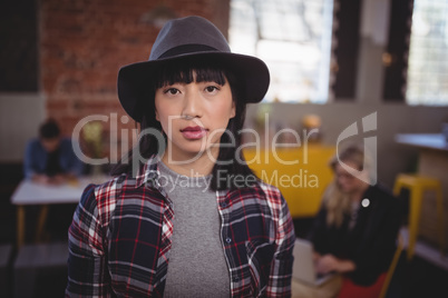 Portrait of confident young woman wearing hat at coffee shop