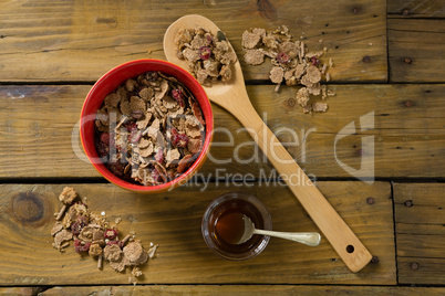 Wheat flakes and honey on wooden table
