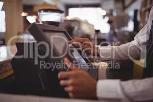 Midsection of waiter touching computer monitor at counter