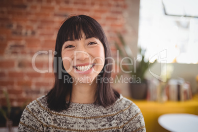 Portrait of smiling attractive young woman standing against brick wall
