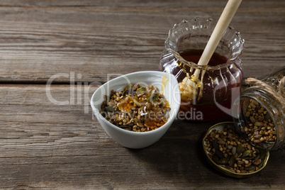 Breakfast cereals and jar of honey on wooden table