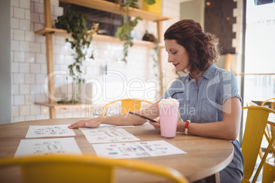 Young woman sitting with papers and drink at coffee shop