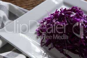 Chopped red cabbage in plate on wooden table