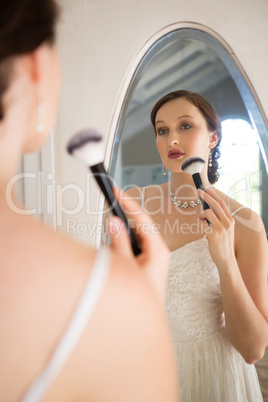 Rear view of beautiful bride applying makeup reflecting on mirror