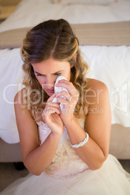 High angle view of sad bride crying while sitting by bed