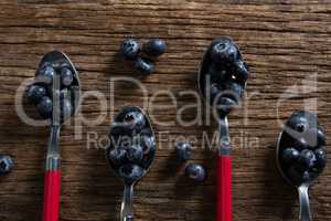 Blueberries in spoon arranged on wooden table