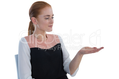 Businesswoman holding imaginary product while sitting on chair