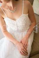 Midsection of beautiful bride wearing necklace sitting on sofa at home