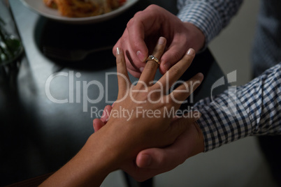 Man putting ring in woman finger