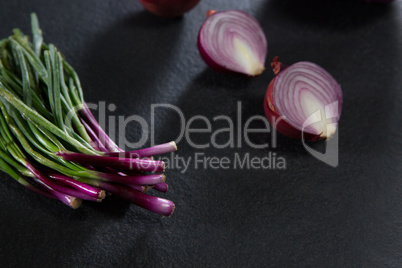 Scallions and halved of onion on black background