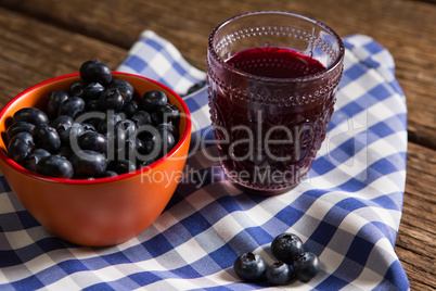 Bowl of blueberries and juice on wooden table