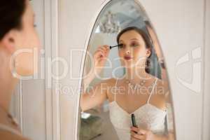 Side view of beautiful bride applying mascara reflecting on mirror