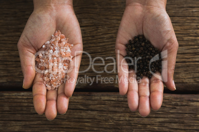 Hands holding sea salt and black pepper seeds