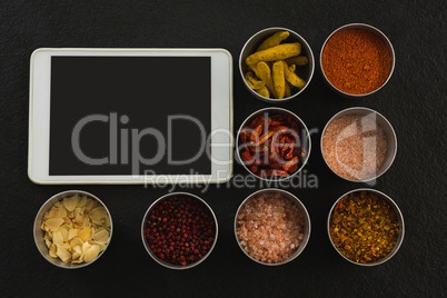 Various spices in bowl with digital tablet