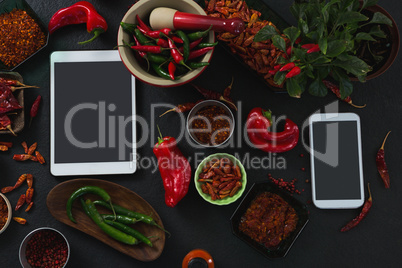 Various spices with digital tablet and mobile phone on black background
