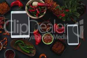 Various spices with digital tablet and mobile phone on black background