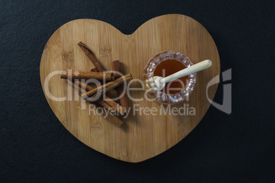 Cinnamon sticks and honey on heart shaped chopping board