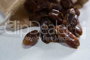 Burlap sack with palm dates spilling out over a white background