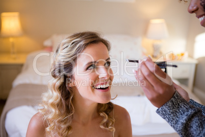 Cropped hands of woman applying makeup to bride in dressing room