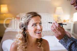 Cropped hands of woman applying makeup to bride in dressing room
