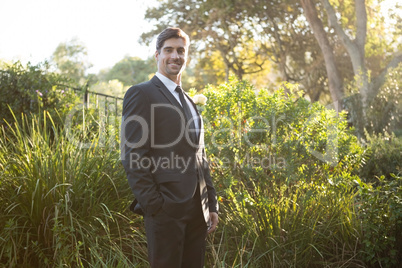 Portrait of confident bridegroom standing in park