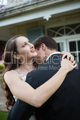 Happy newlywed couple embracing in park