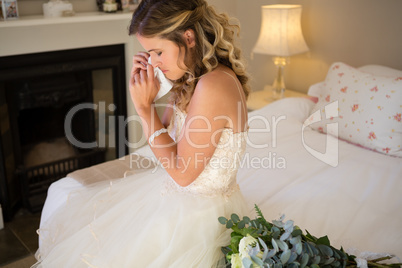 Sad bride crying while sitting on bed