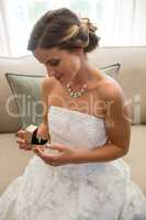Beautiful bride looking wedding ring while sitting on sofa at home