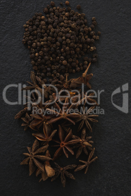 Star anises and black peppers on black background