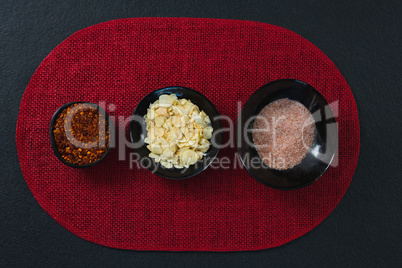 Red pepper flakes, roasted coconut chips and salt on aplace mat