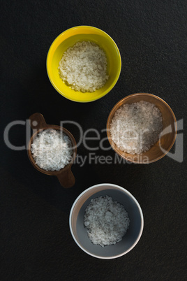 Salt in various bowl on black background