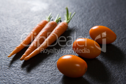 Carrots and tomatoes on black background