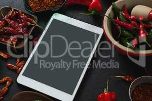 Various spices with digital tablet on black background