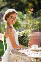 Portrait of smiling bride holding bouquet while sitting on chair