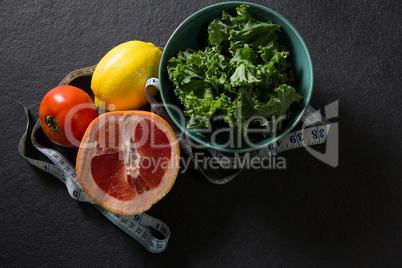 Mustard greens in bowl with citrus, tomato and tape measure