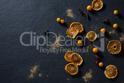 Dried orange with star anise and golden berries on black background