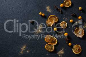 Dried orange with star anise and golden berries on black background