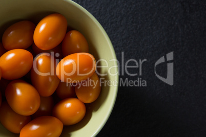 Tomatoes in bowl on black background